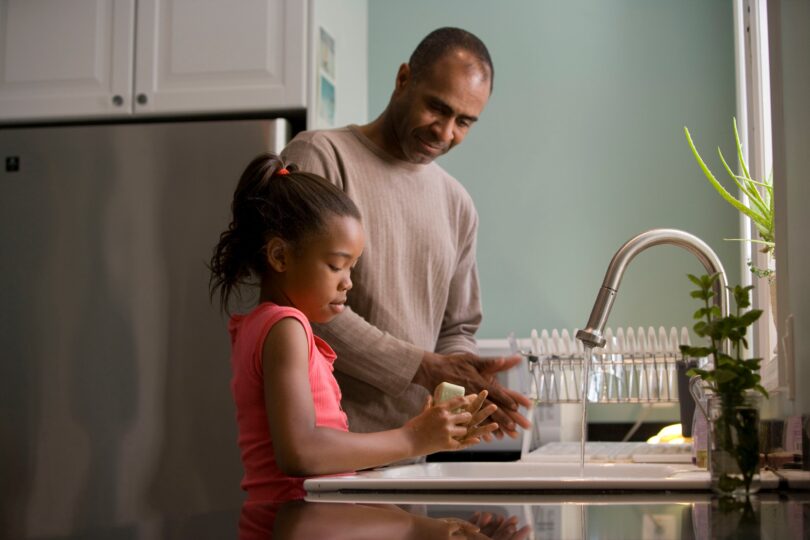 Father and daughter at sink. Christian parenting